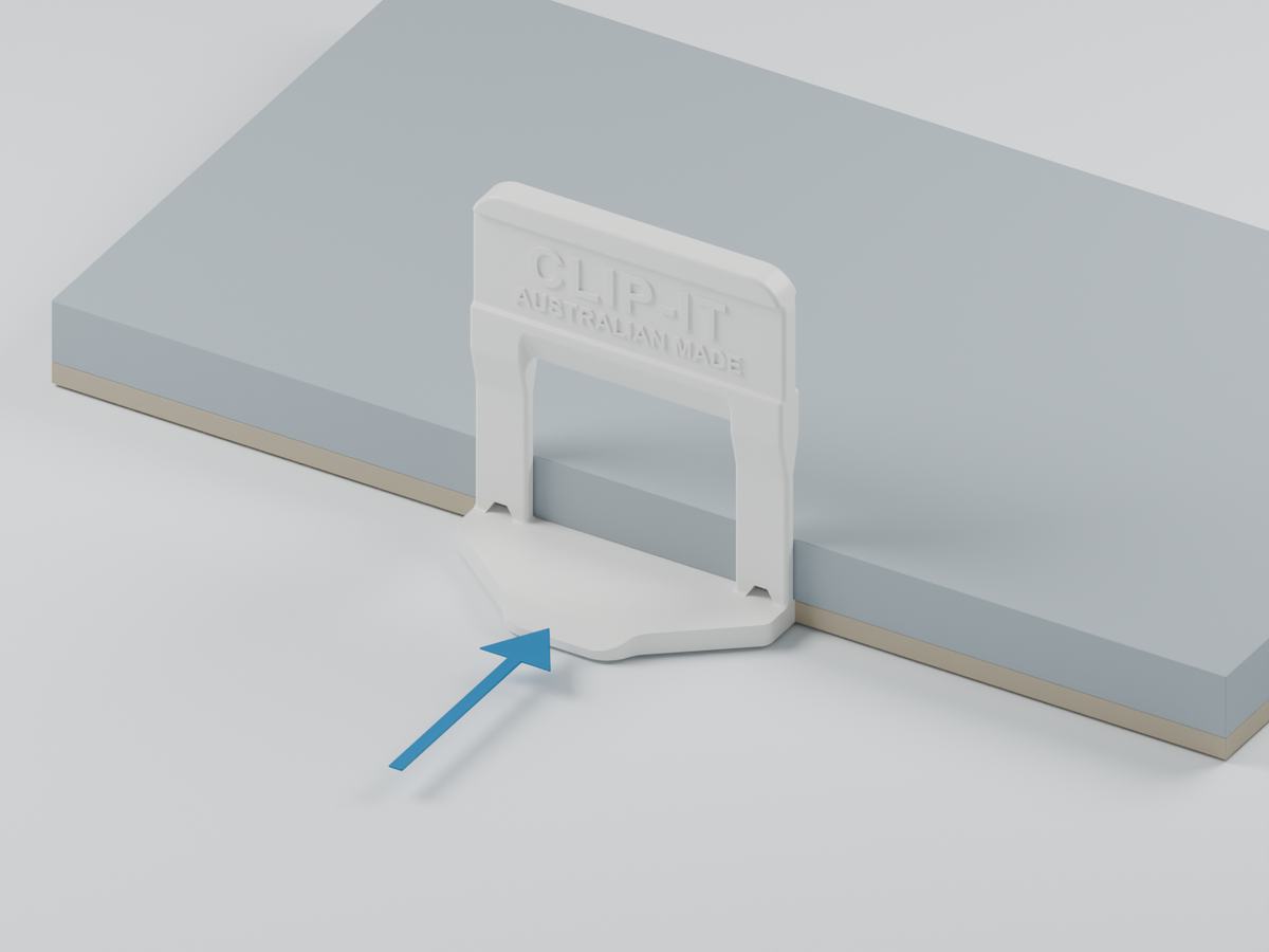 White CLIP-IT® clip with its base under the exposed edge of the first tile